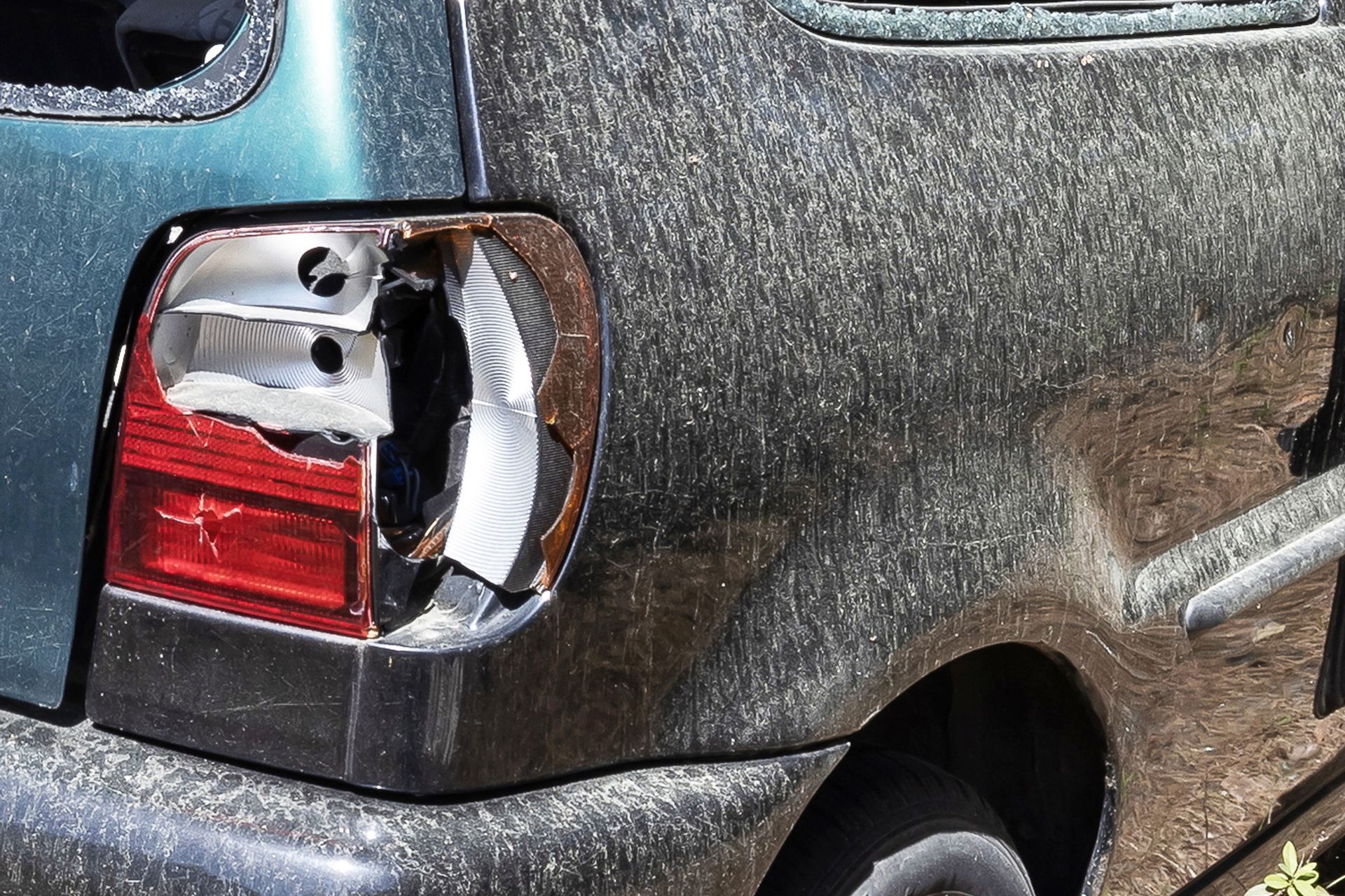 A dirty car with a broken tail light