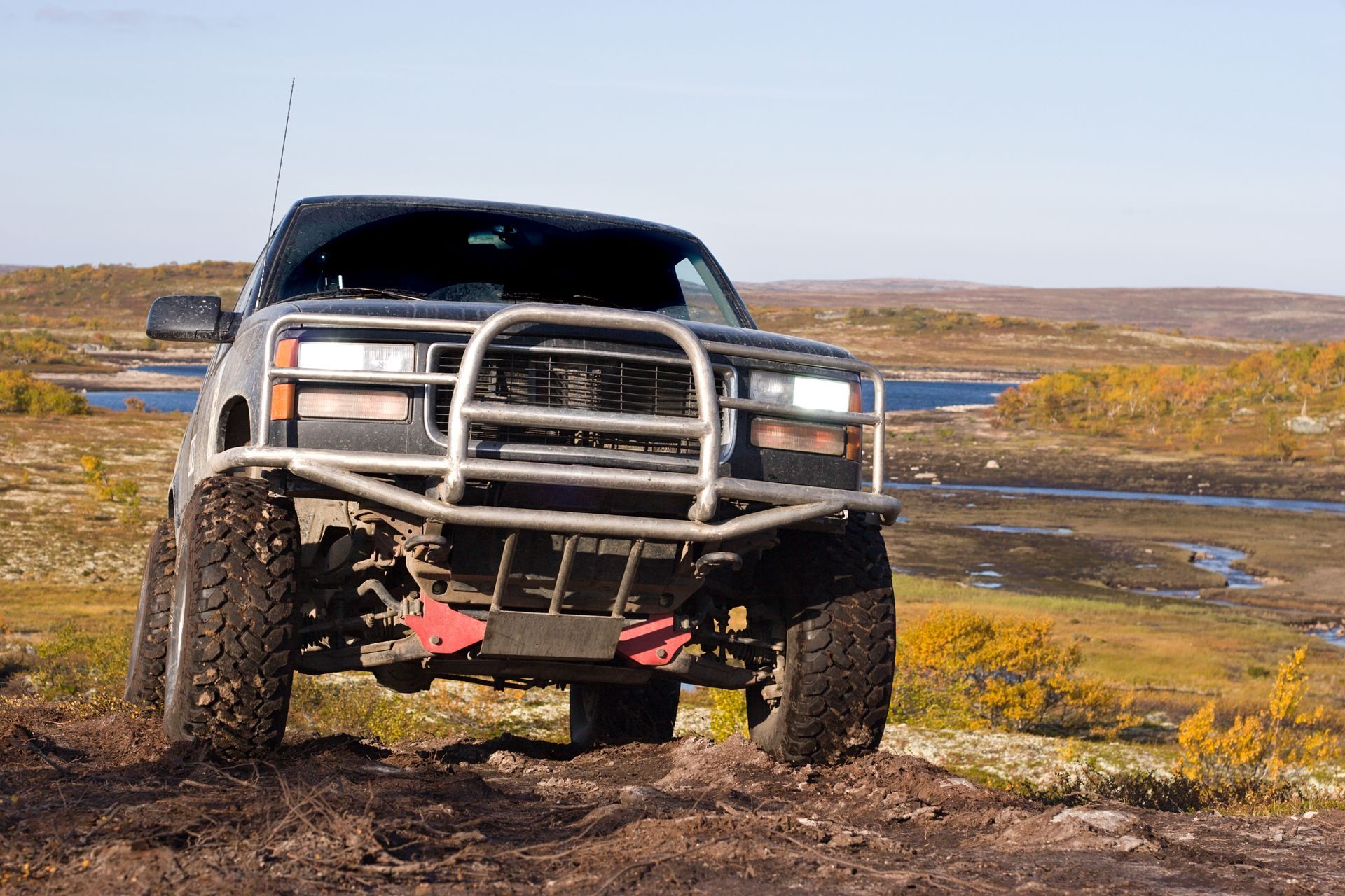 A truck is driving down a dirt road next to a body of water.