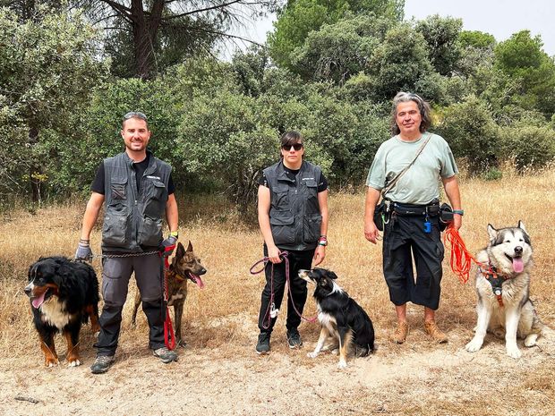 Un grupo de personas y sus perros están parados en un campo.