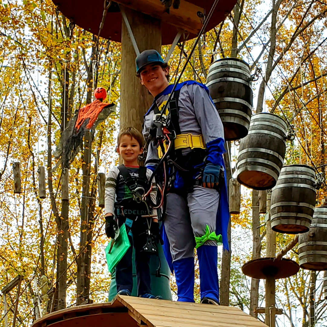 Batman helping child climb on high ropes course