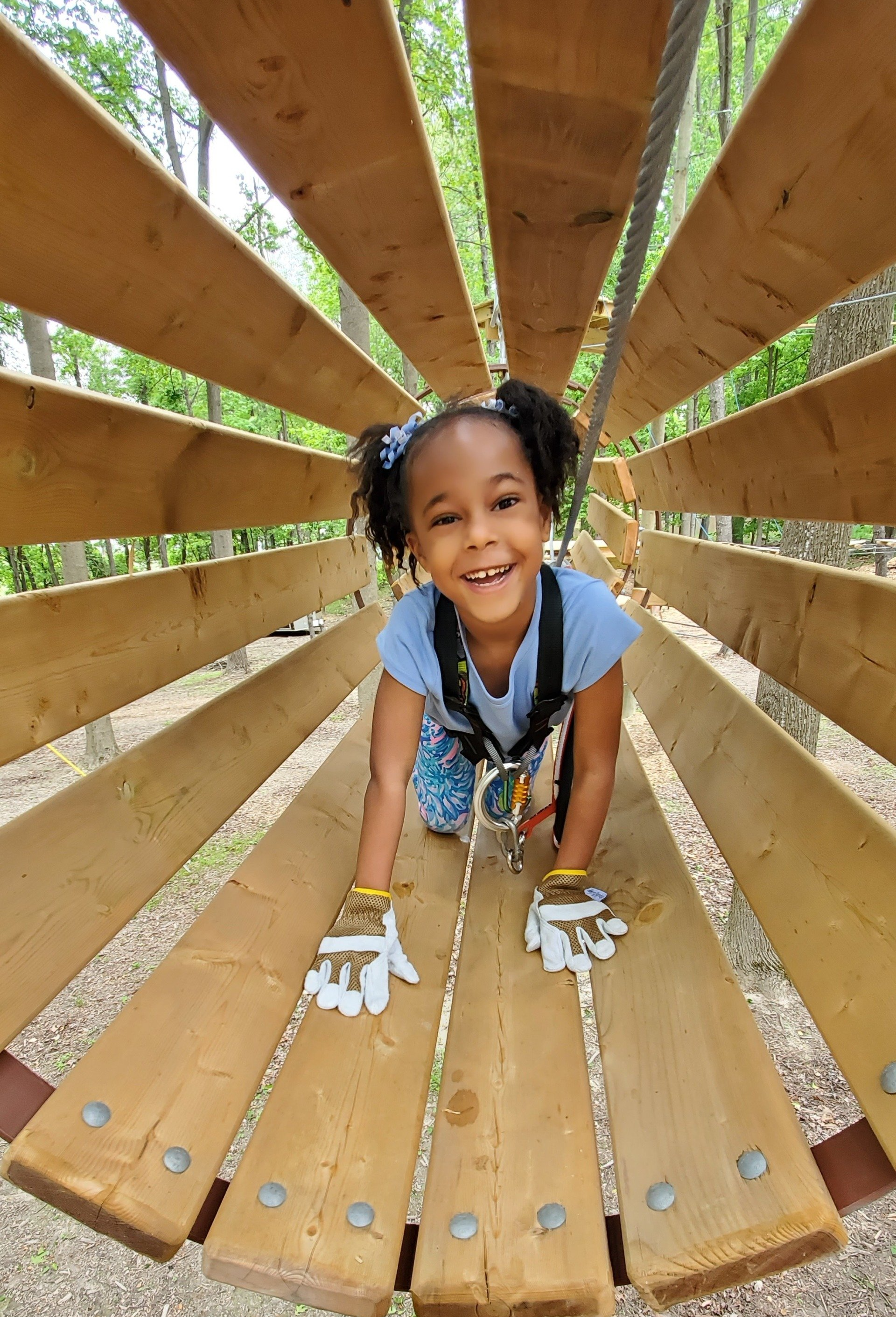 Young African American girl climbing through ropes course tunnel obstacle
