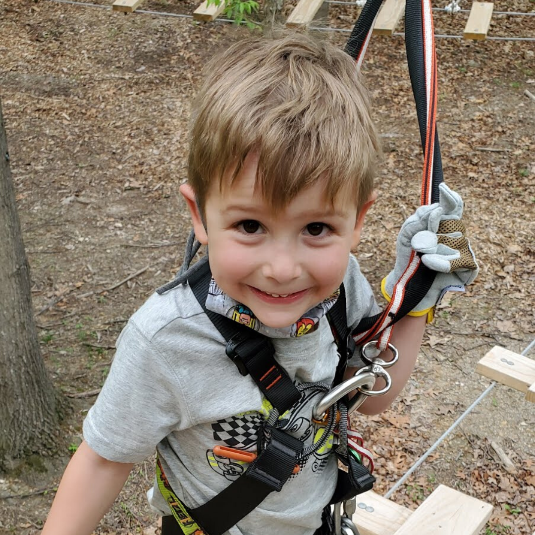 Young boy smiling as he climbs high ropes course