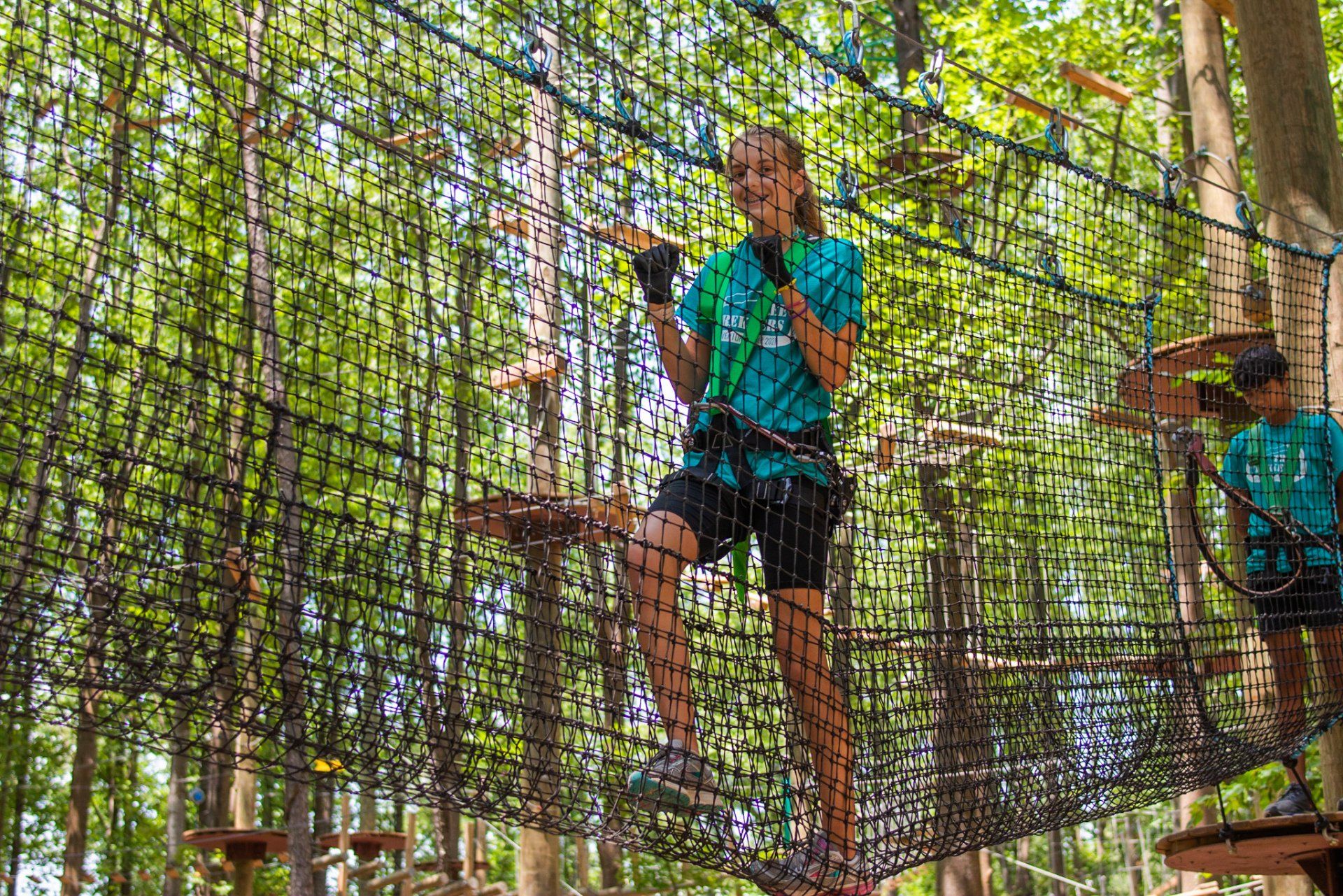 Young female climbing through cargo net at challenge course