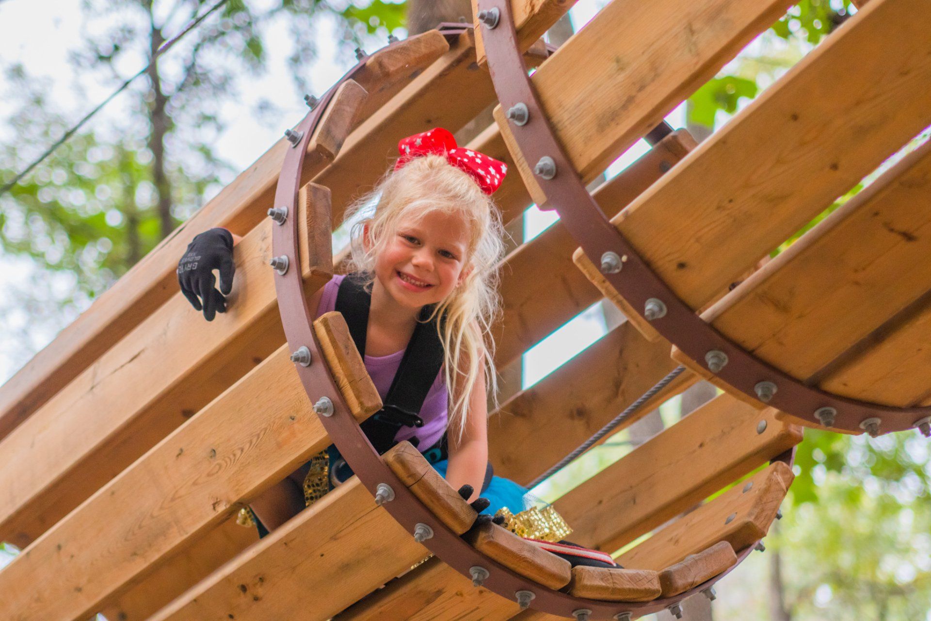 Young girl climbing through tunnel obstacle on high ropes course