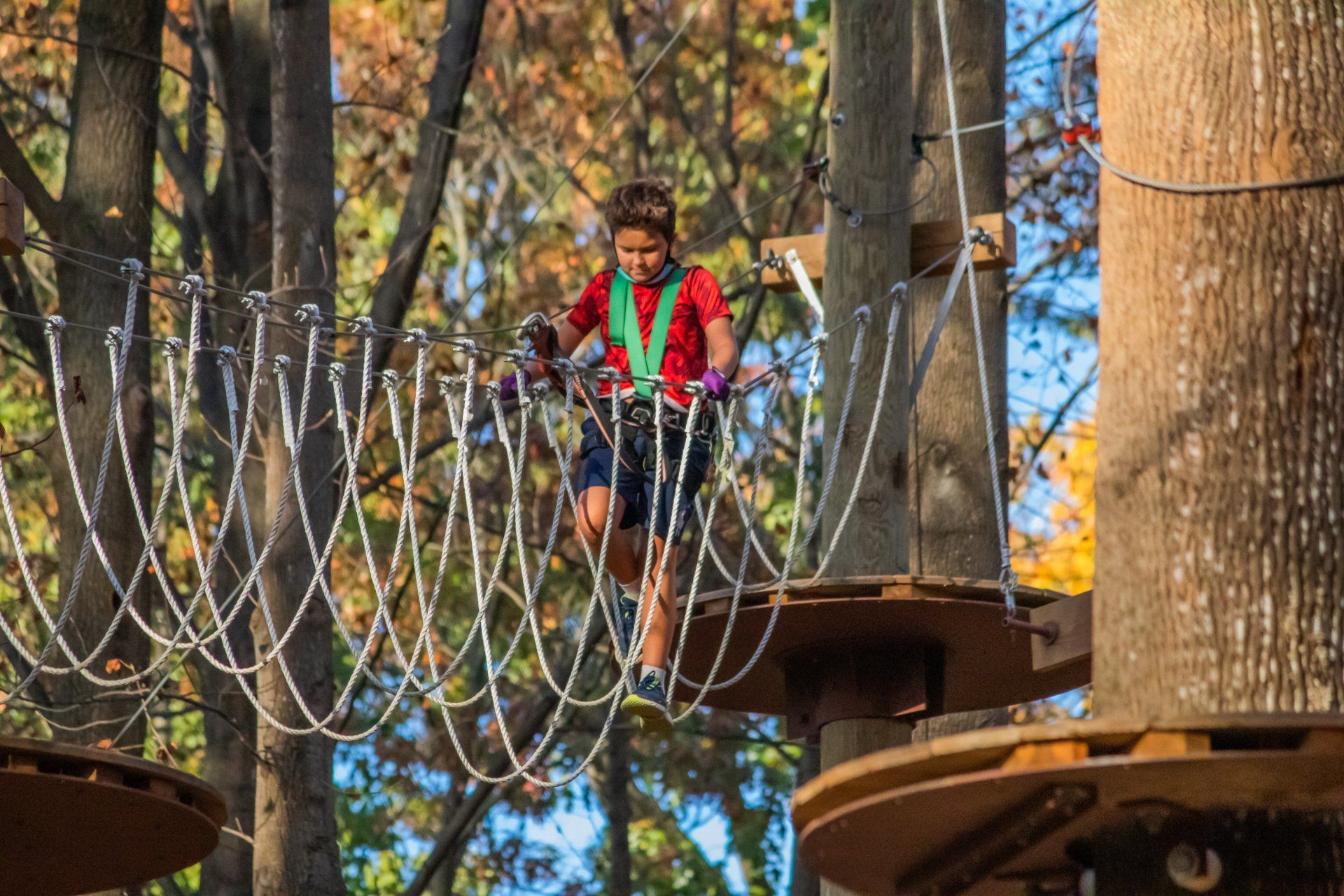 Adolescent boy climbing on rope bucket element
