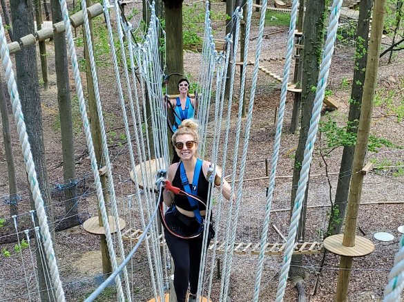Female adult climbing on double blue high ropes obstacle