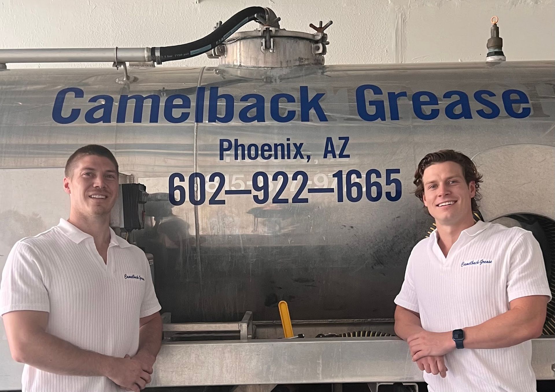 Two men in white shirts stand in front of a Camelback Grease tanker in Phoenix, AZ.