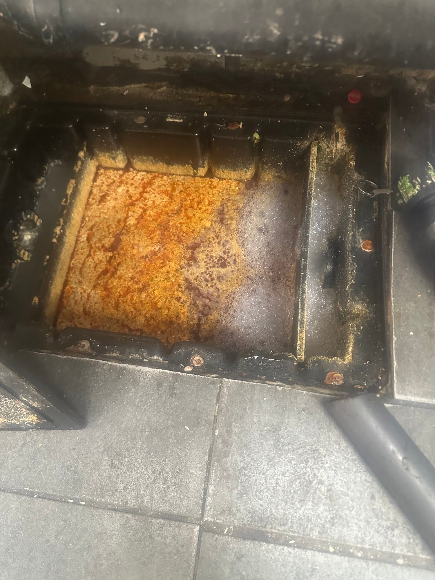 Rust-covered interior compartment of a metal appliance. Brown and orange stains, surrounded by black frame.