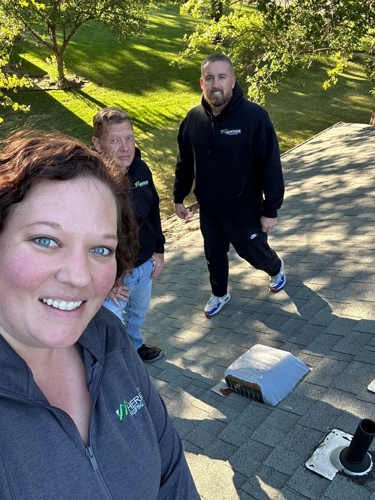 A woman and two men are standing on top of a roof.