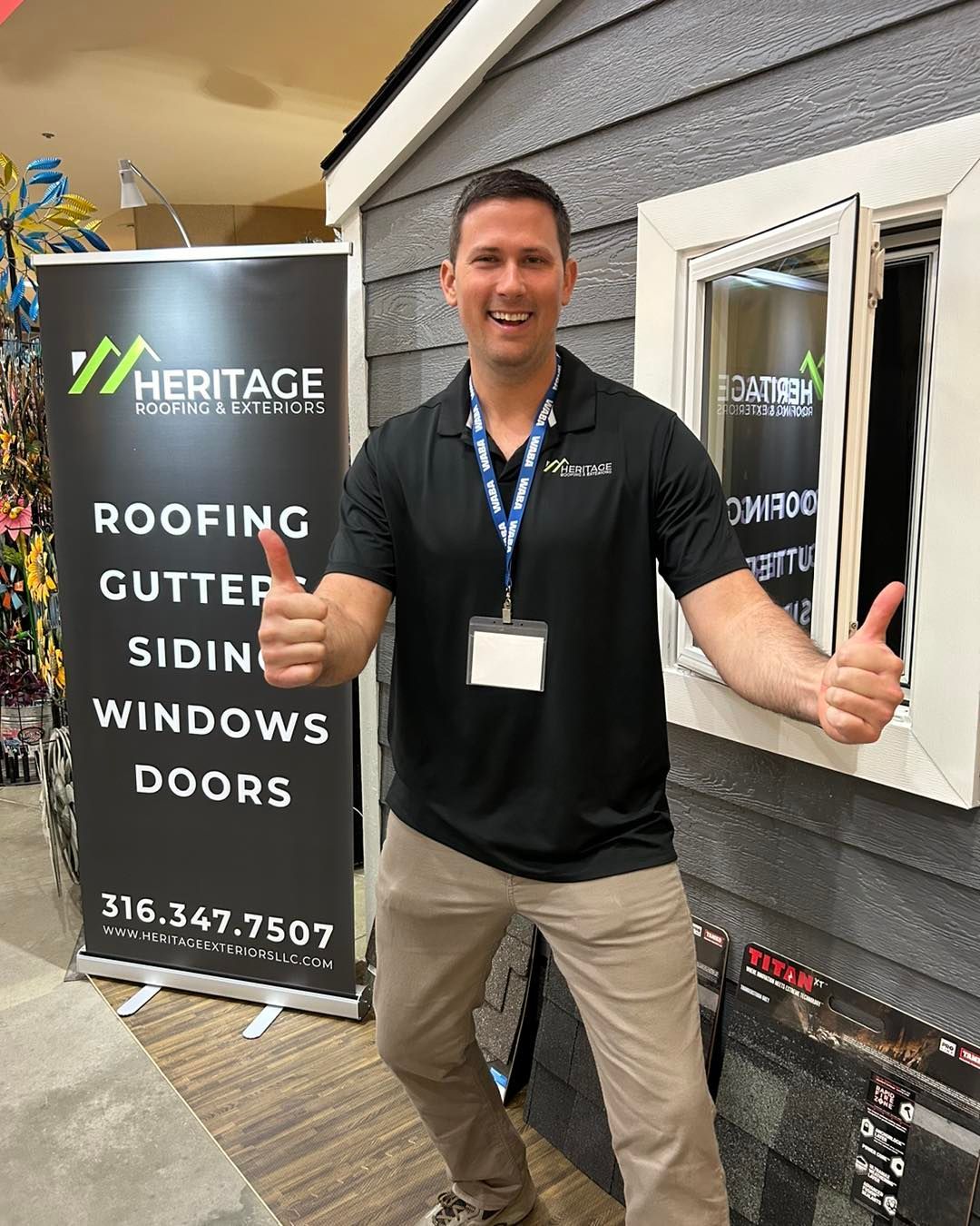 A man is giving a thumbs up in front of a sign that says roofing gutter siding windows doors.