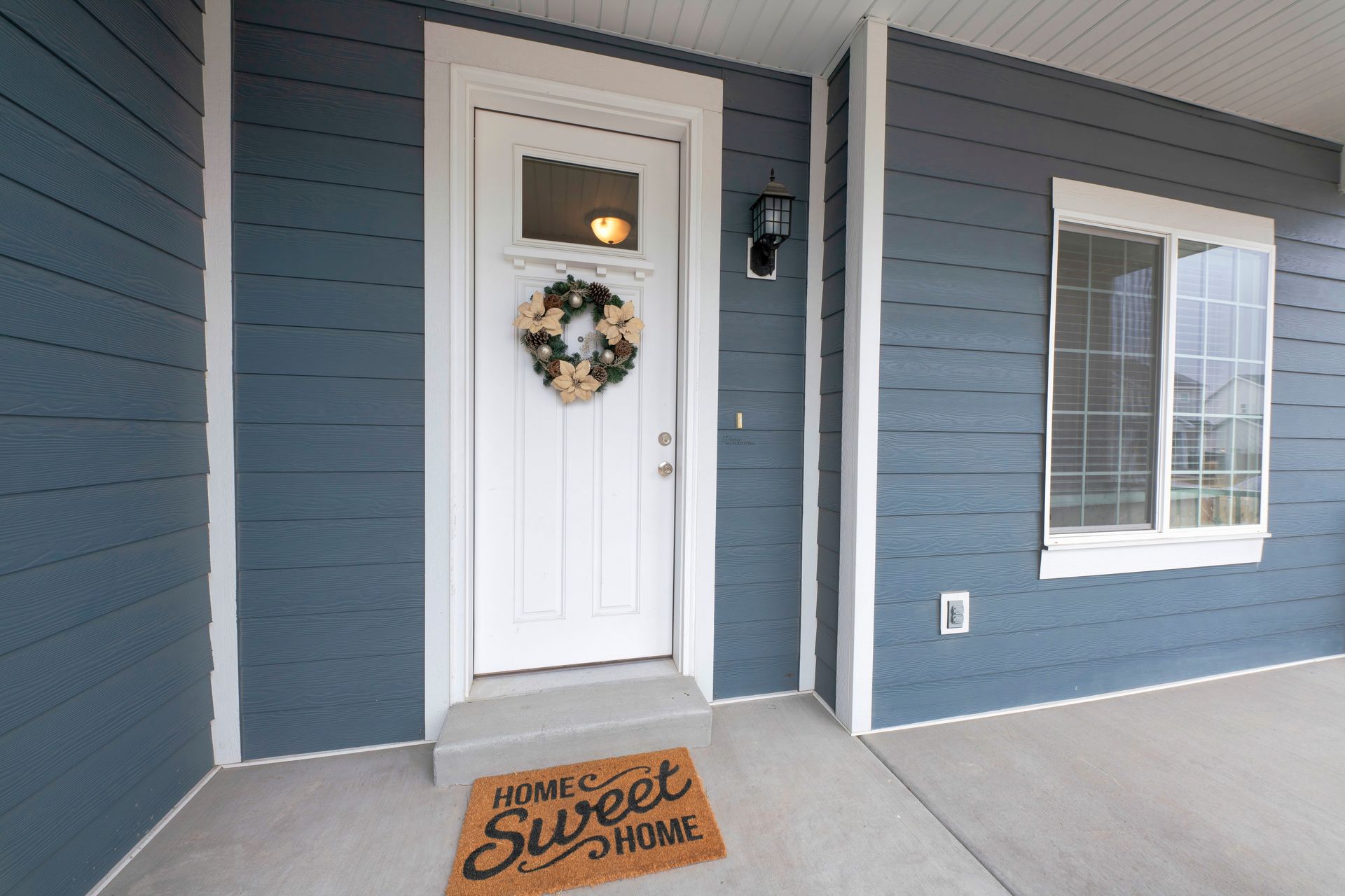 A blue house with a white door and a welcome mat