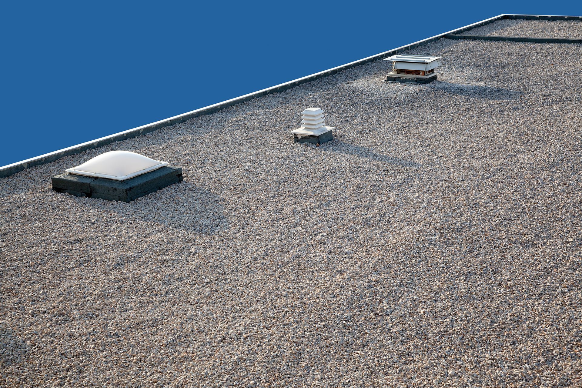 A roof with a few skylights on it and a blue sky in the background.