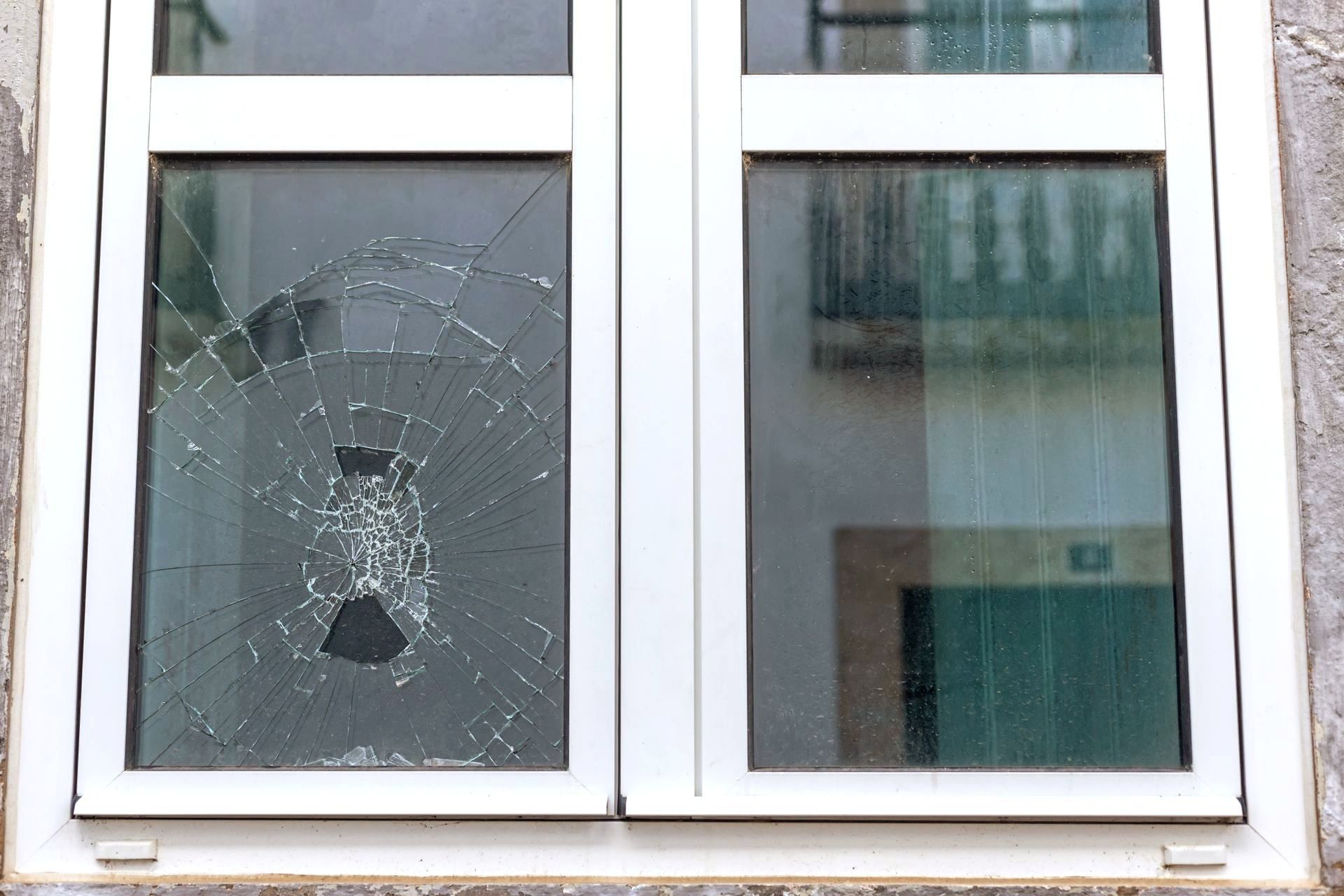 A broken window on a building with a white frame