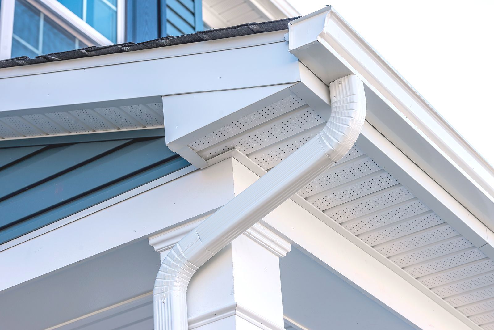 A close up of a white gutter on the side of a house.