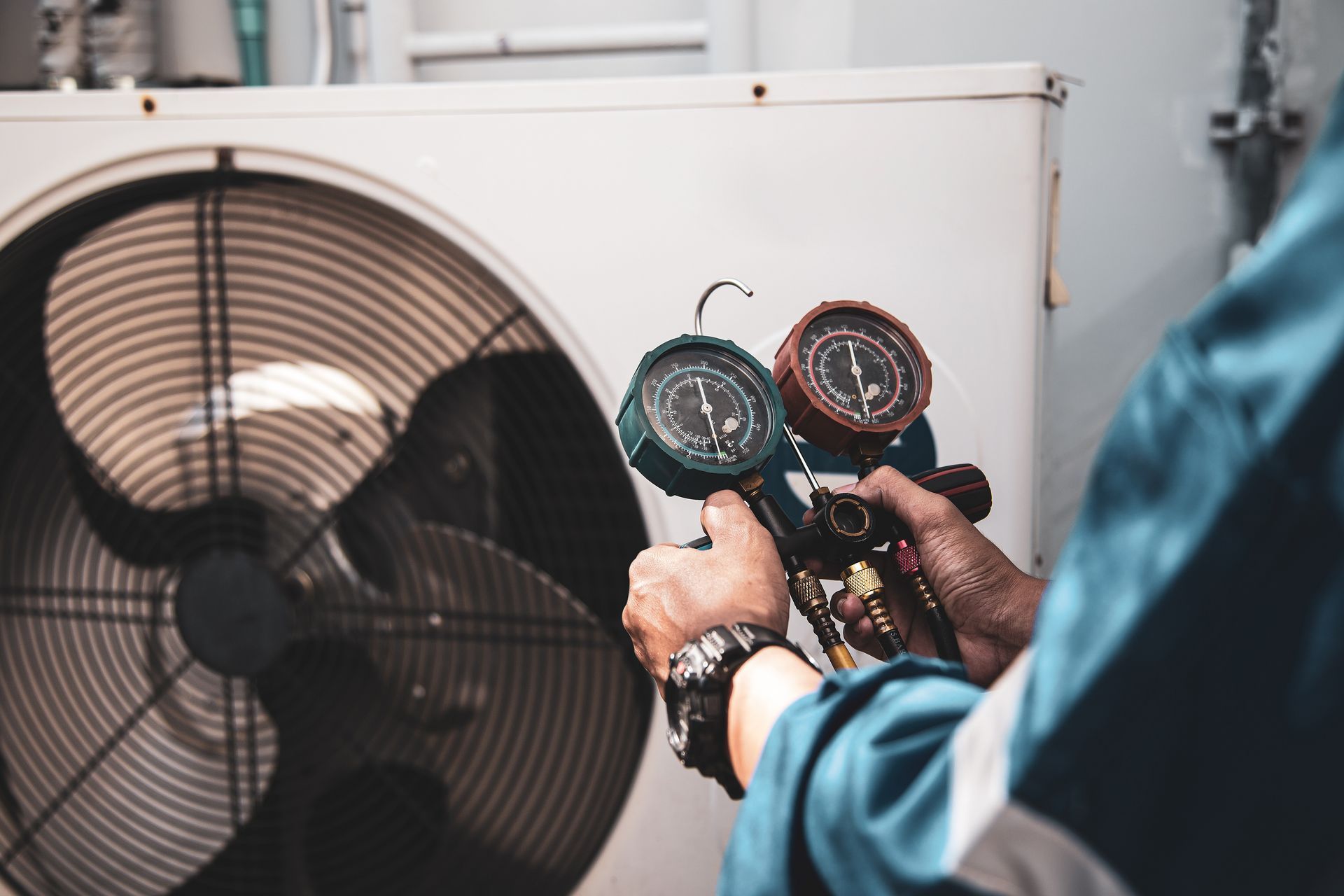 A man is holding two gauges in front of a fan.