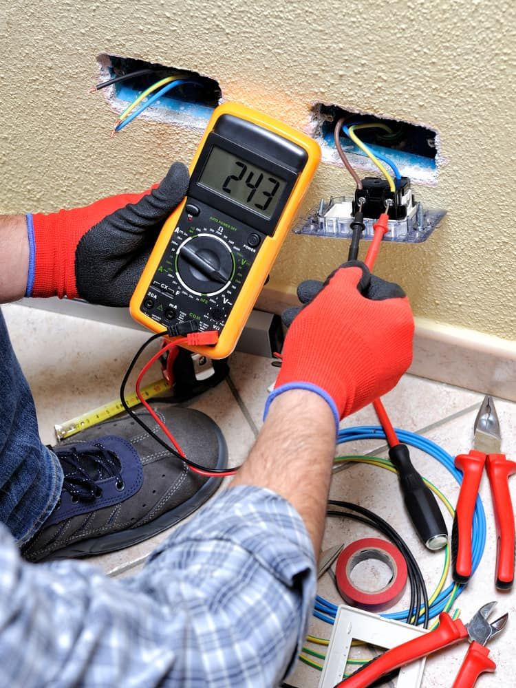 Electrician tests voltage at an electrical outlet with a multimeter