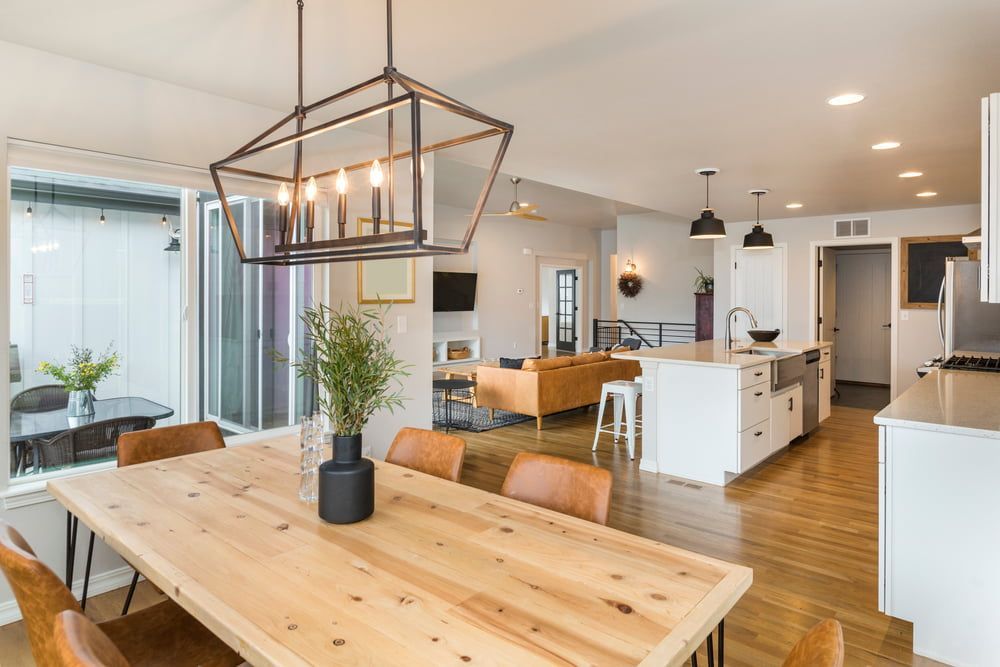 Open-concept dining and kitchen area with wooden table and light fixtures