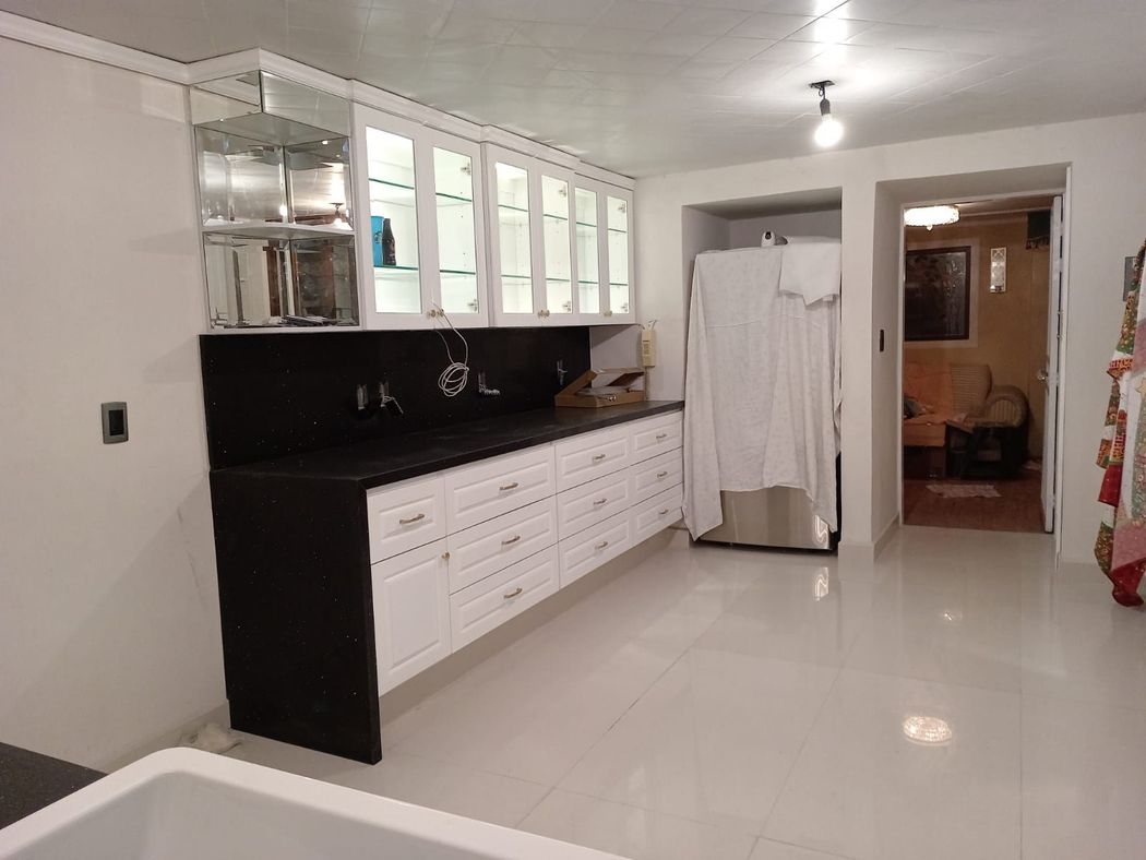 Una cocina con gabinetes en blanco y negro y un refrigerador.