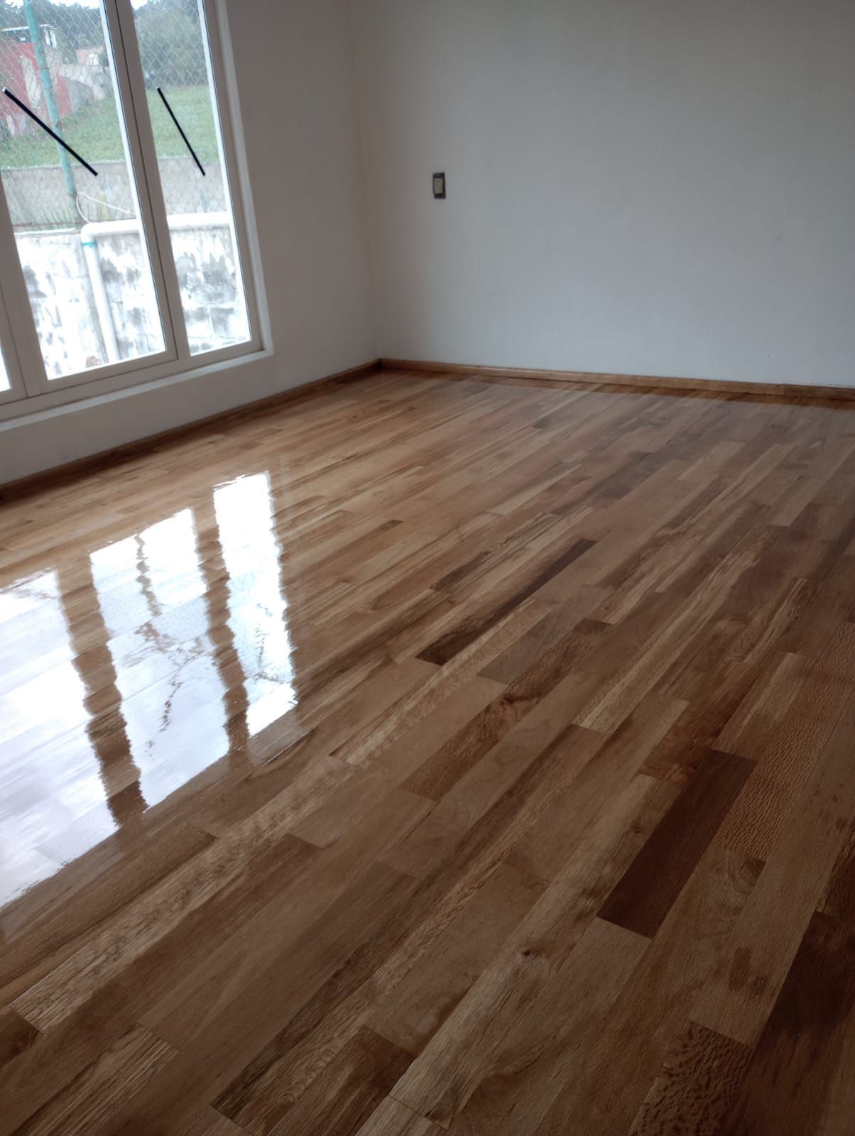 Una habitación con suelo de madera y una ventana.