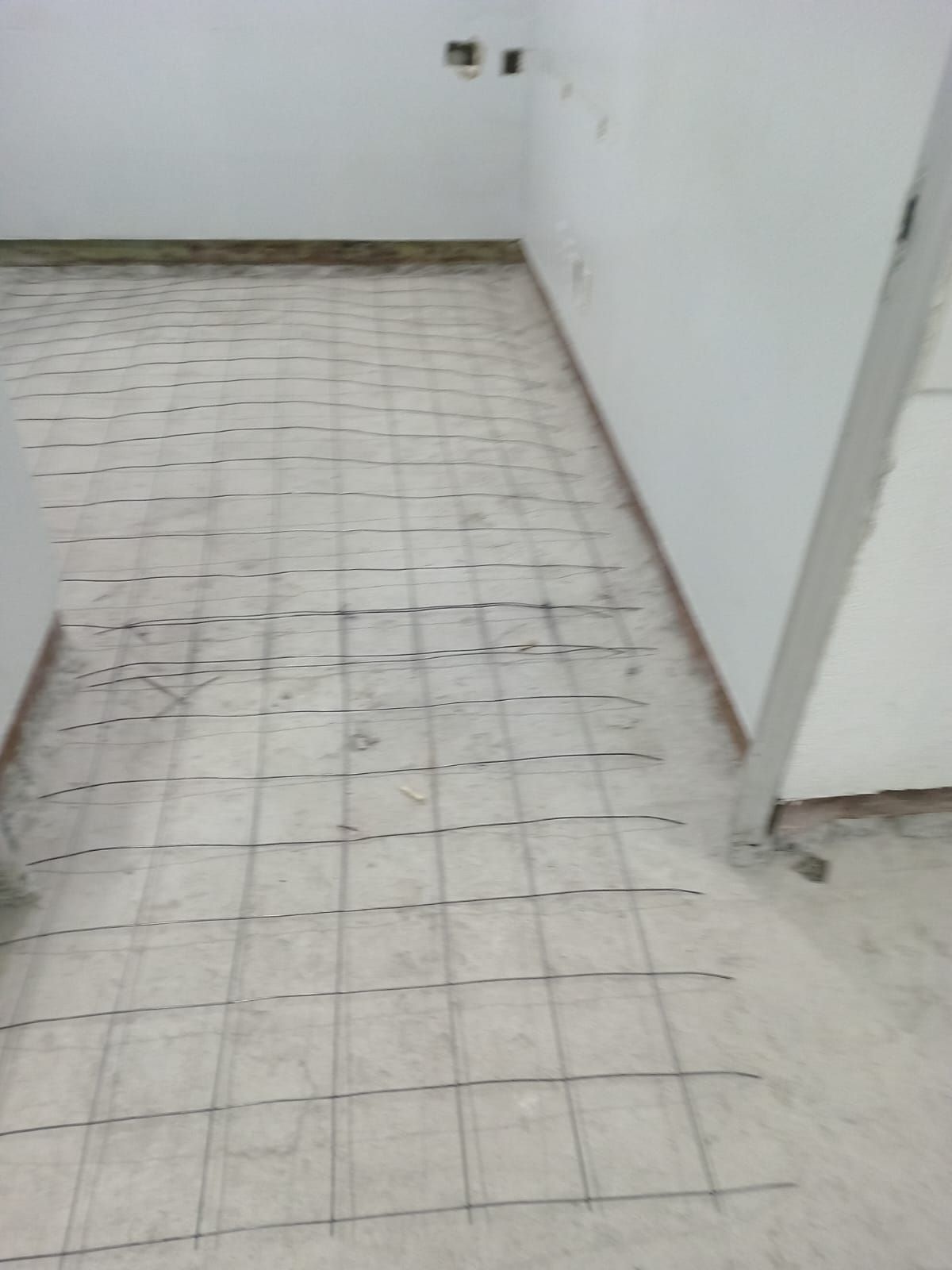 Una habitación con suelo de baldosas y una pared blanca.