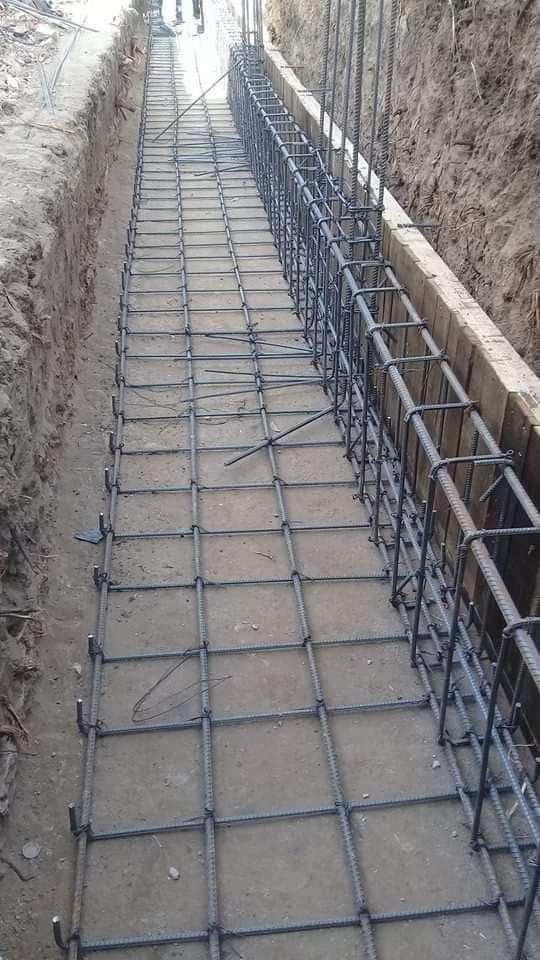 Una fila de barras de metal colocadas encima de un suelo de tierra.