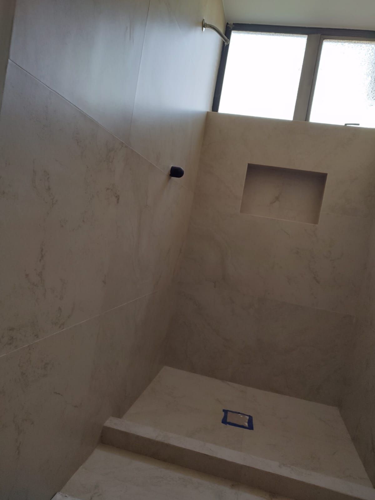 Un baño con ducha a ras de suelo y ventana.