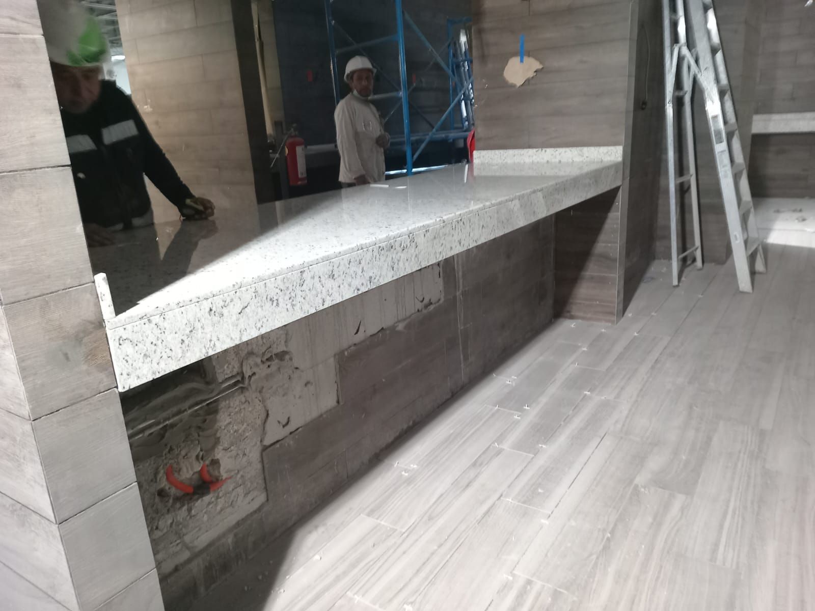 Un hombre está parado detrás de un mostrador en una habitación con una escalera.