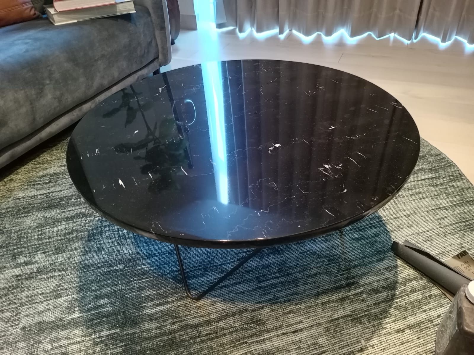 Una mesa de café de mármol negro se encuentra sobre una alfombra en una sala de estar.