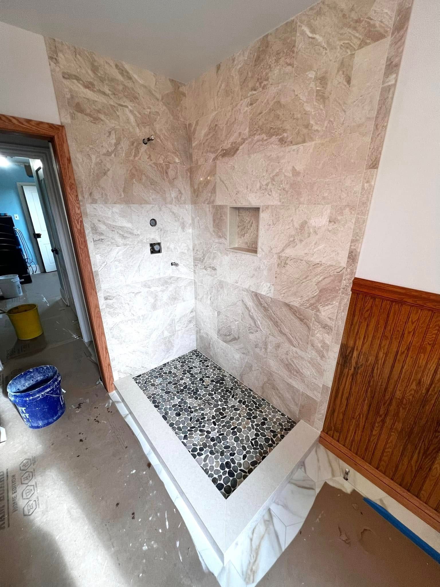 A bathroom with a walk in shower and a tiled wall.