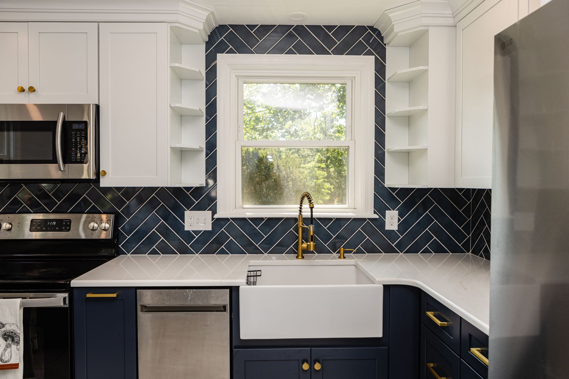 A kitchen with blue cabinets , white cabinets , stainless steel appliances , a sink , and a window.