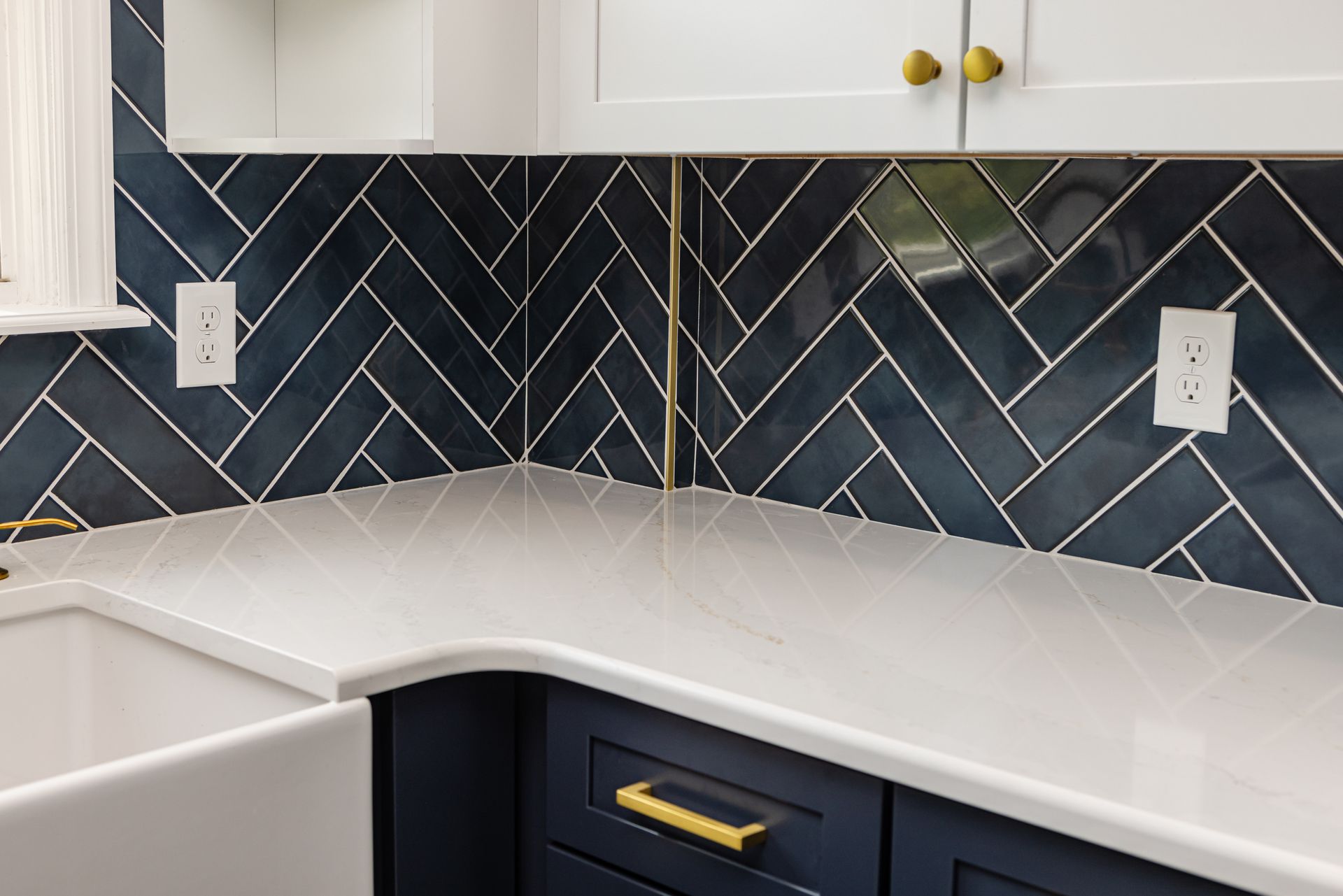 A kitchen with blue cabinets , white counter tops , and a sink.