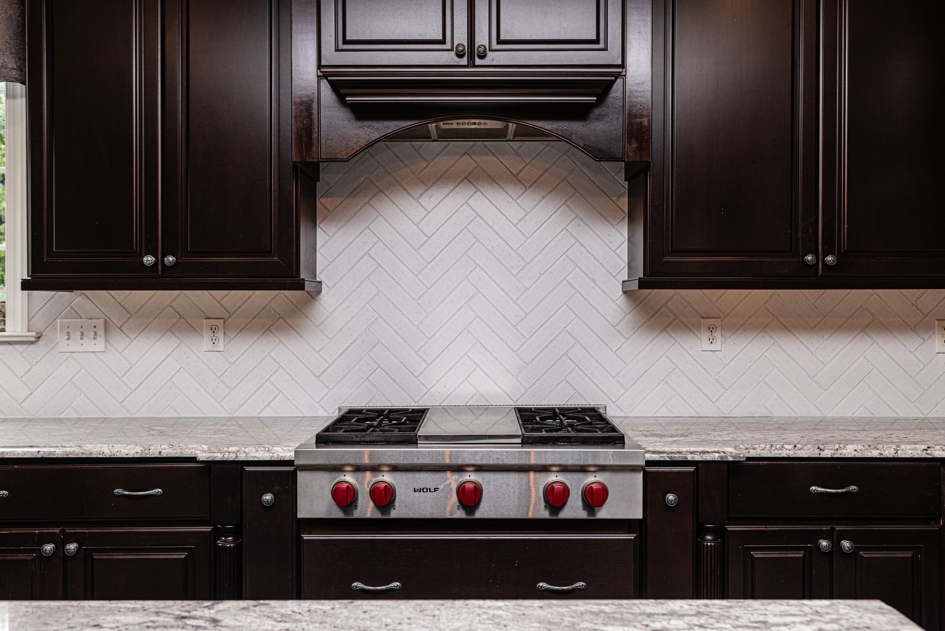 A kitchen with dark cabinets and a stove top oven.