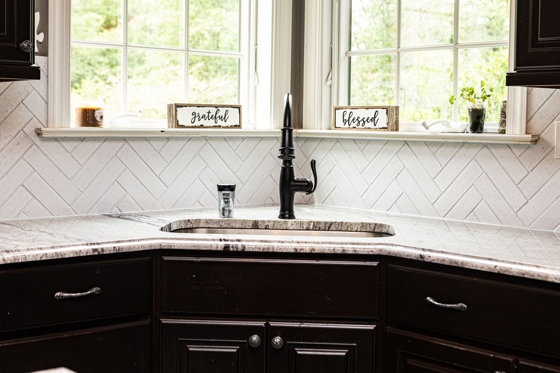A kitchen with a sink , cabinets , and a window.