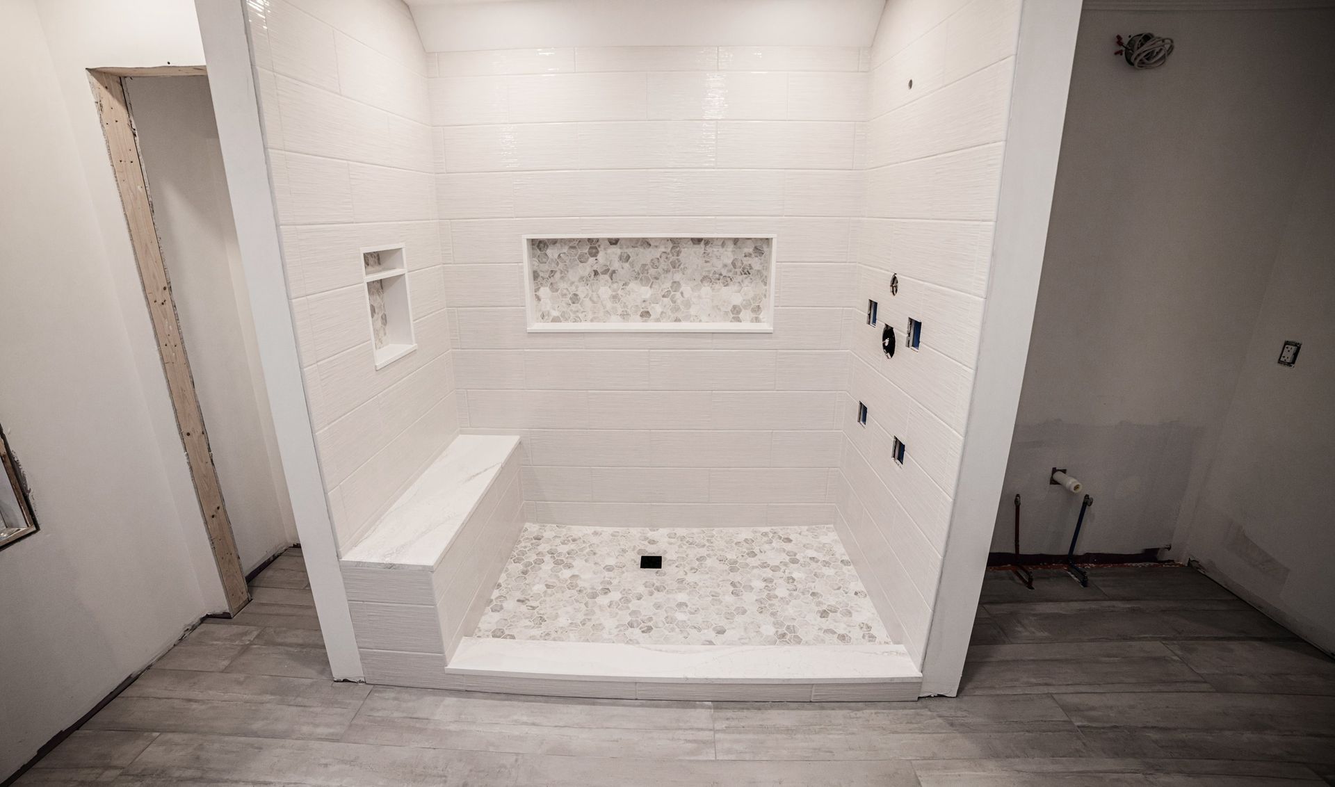A bathroom with a walk in shower and a bench.
