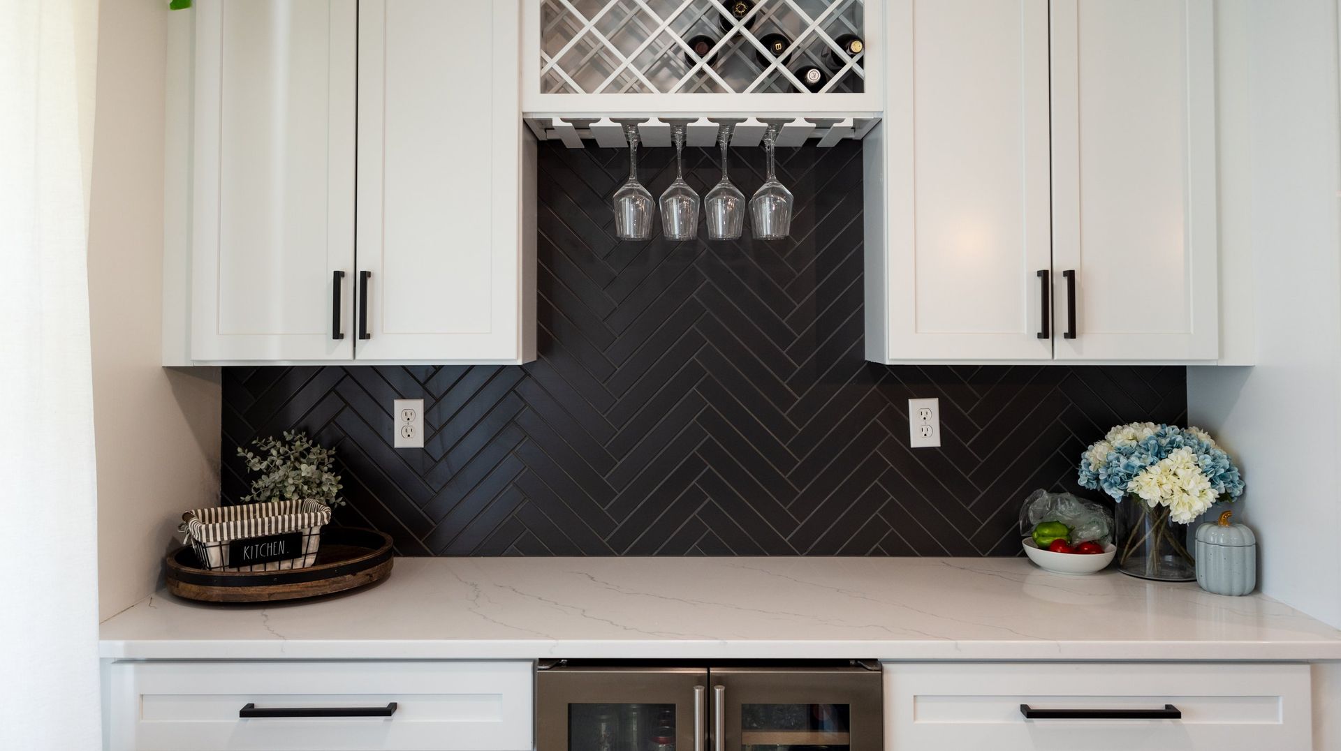 A kitchen with white cabinets and a wine rack on the wall.
