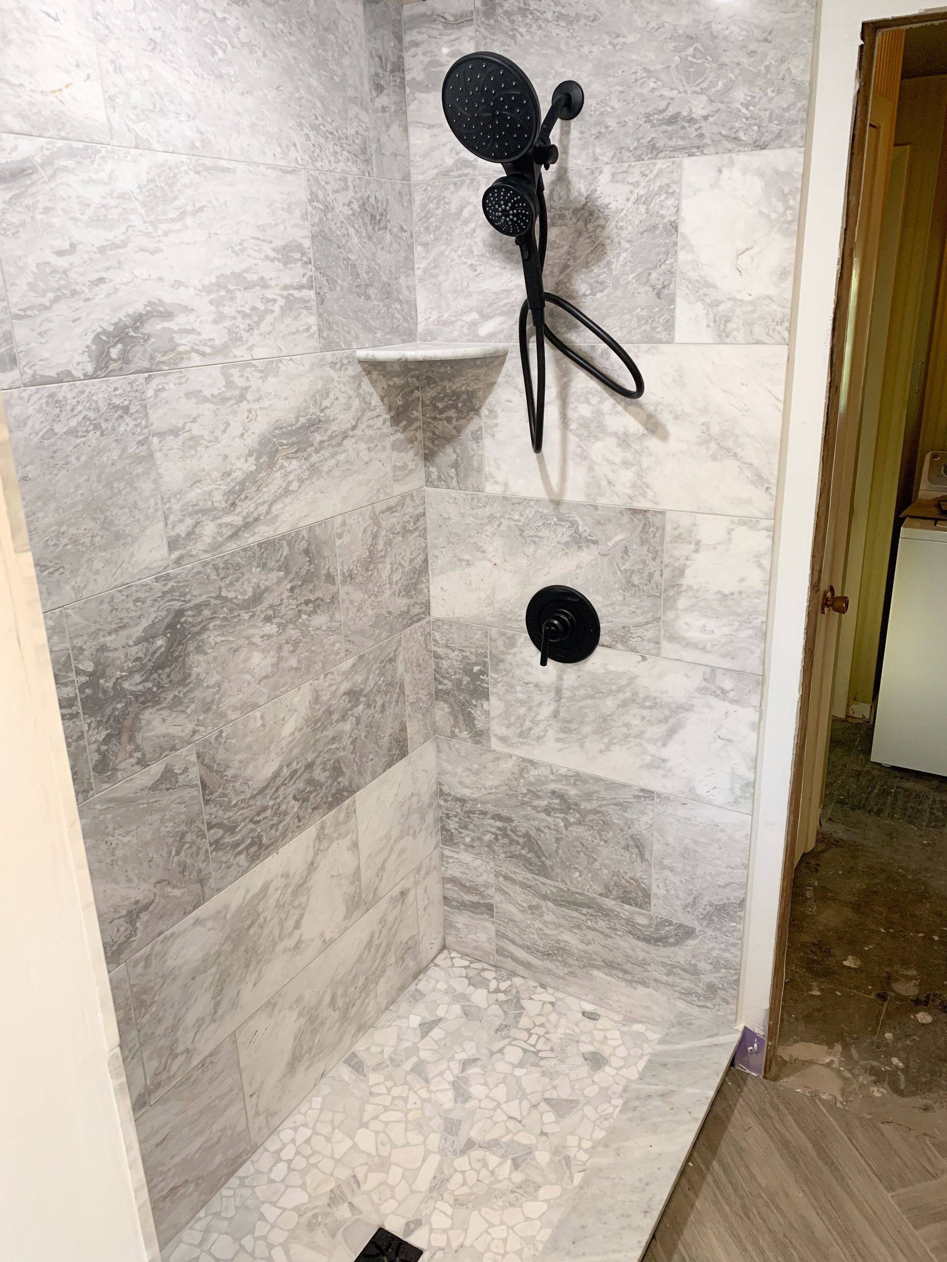 A bathroom with a walk in shower and a black shower head.