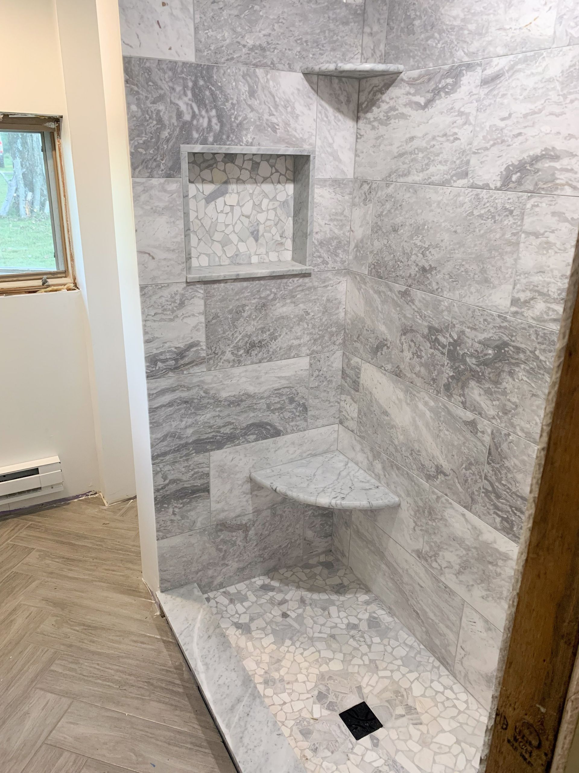 A bathroom with a walk in shower and a window.