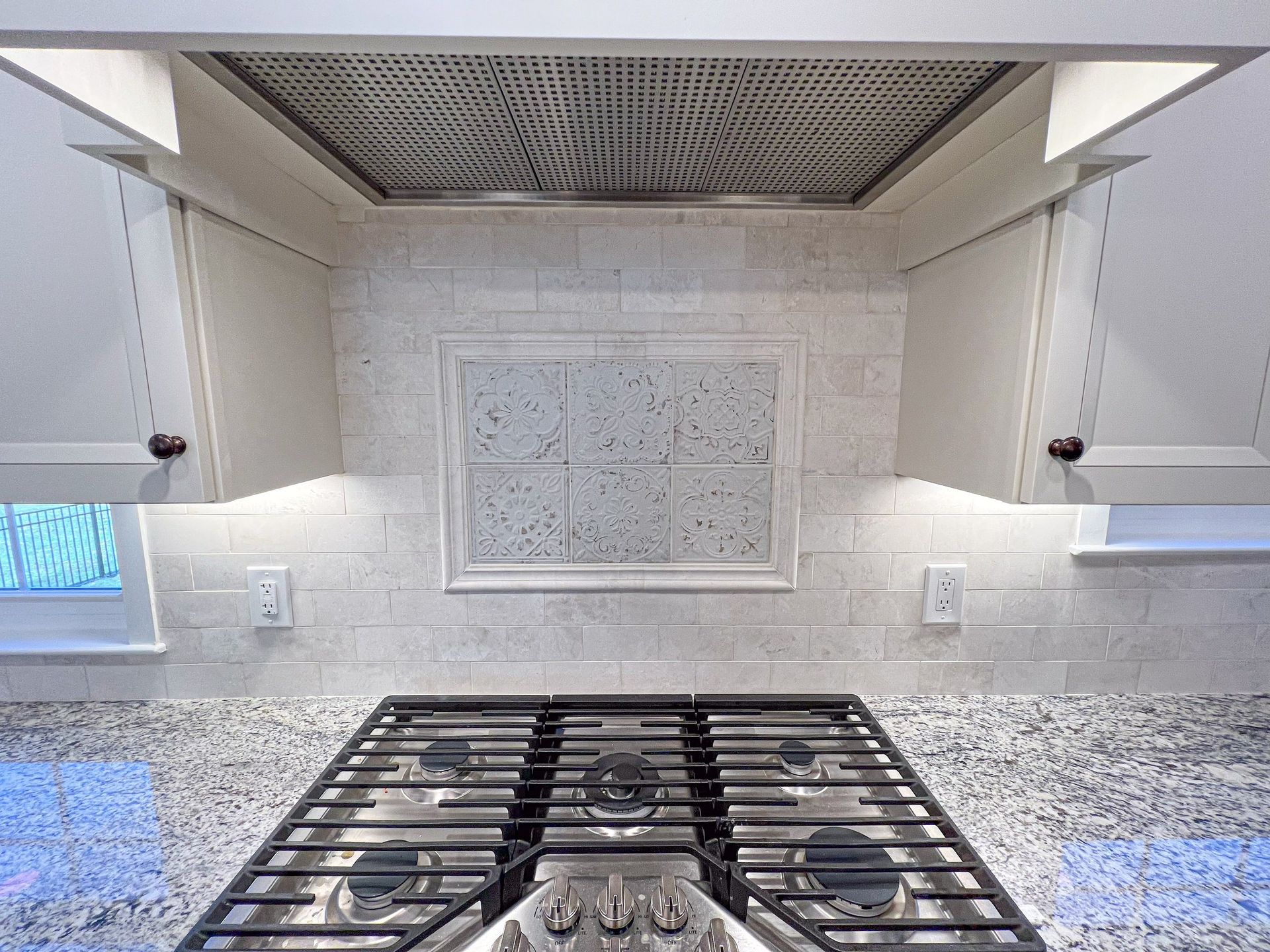 A stove top oven is sitting on top of a granite counter top in a kitchen.