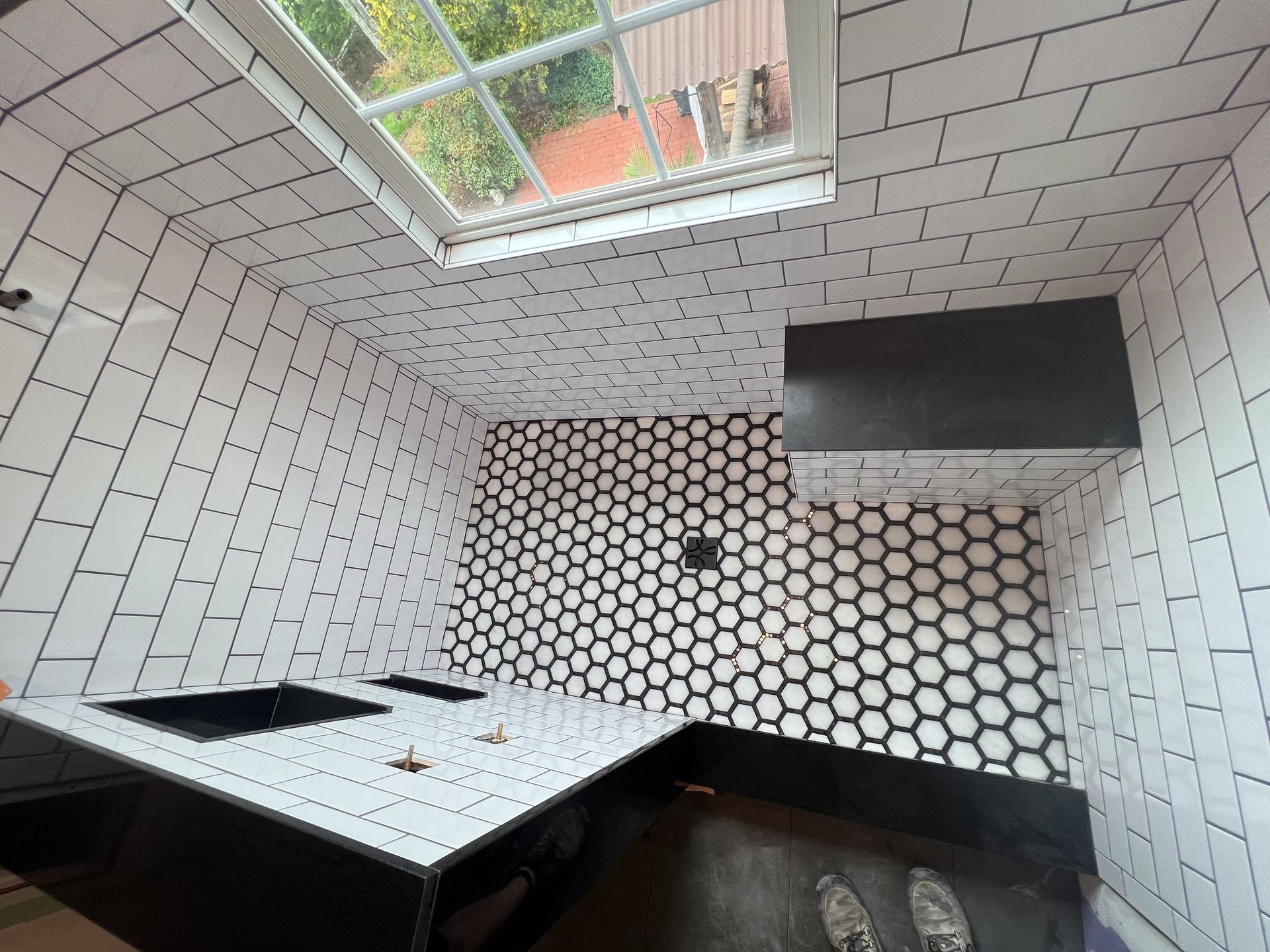A bathroom with black and white tiles and a window.