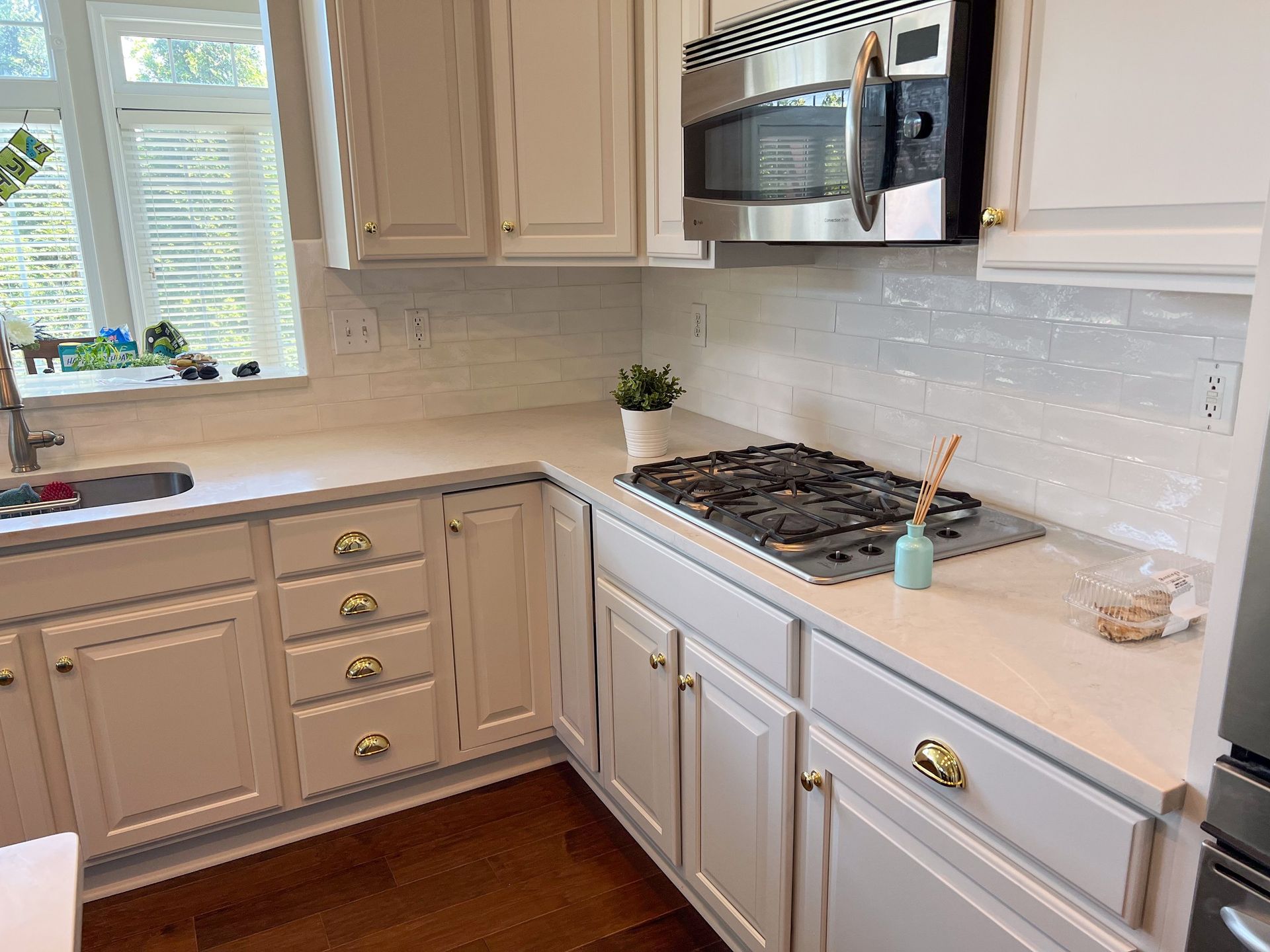 A kitchen with white cabinets , a stove top oven , a microwave , and a sink.