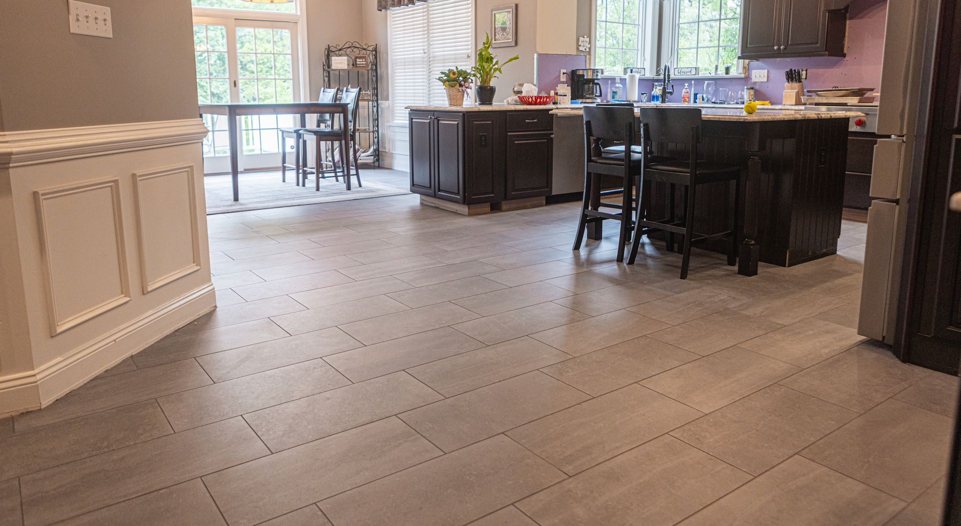 A kitchen with a tiled floor and a dining room in the background.