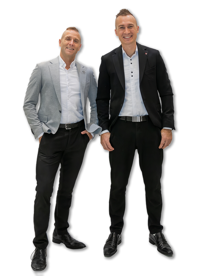 Andy and Steven standing together with casual business suits on, smiling.