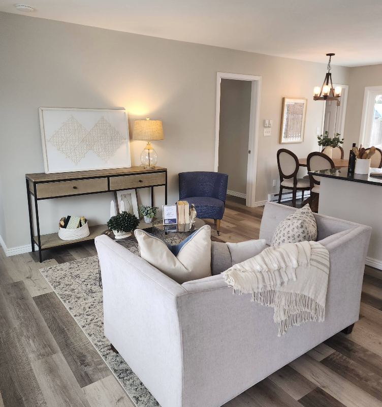 A bright, modern living room featuring a gray sofa, a blue armchair, and a console table against a neutral wall.