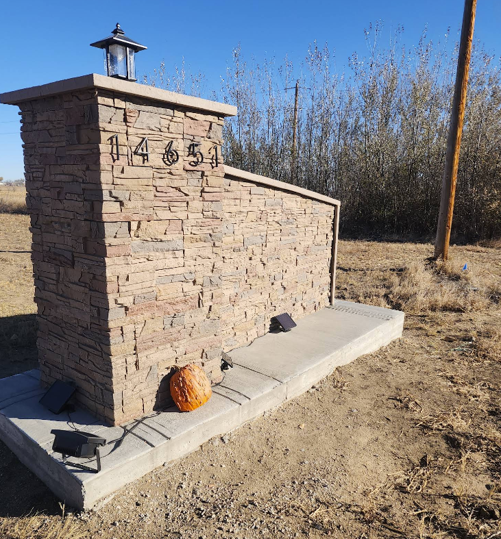 A stone address monument featuring the number 14651, a top lantern, and a small pumpkin on its concrete base.