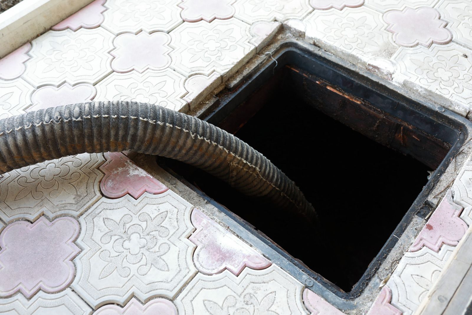 A hose is coming out of a manhole cover.