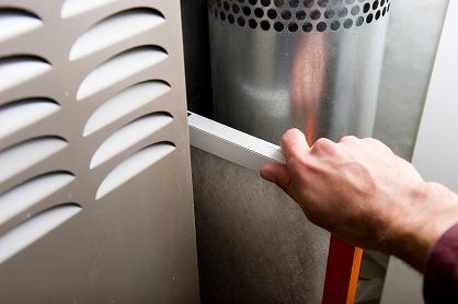 A technician changes a furnace filter.