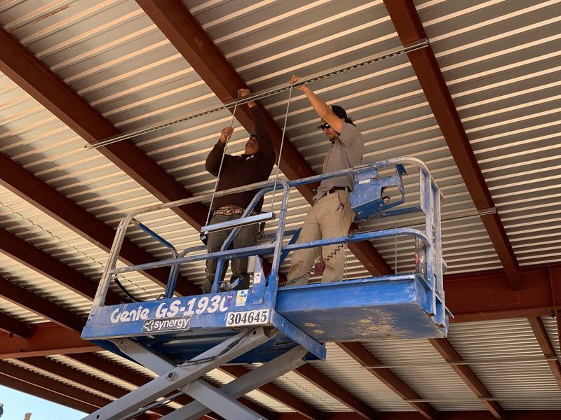 Two men on an elevated platform install ducts.
