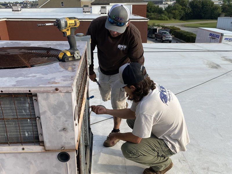Speir Heating and Air technicians service an older HVAC unit.