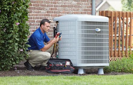 An air conditioning technician inspects an air conditioner.