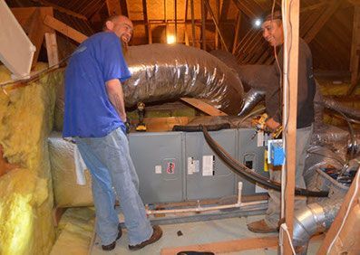 Two men install HVAC ducts.